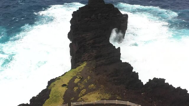 Aerial drone view of Puits des Francais on a stormy day with high breaking waves, cliffs and mountain range in the background, Saint-Philippe, Reunion.