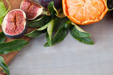 Closeup of orange tangerine, figs and grape fruit mix and green leaves on brown and grey color...