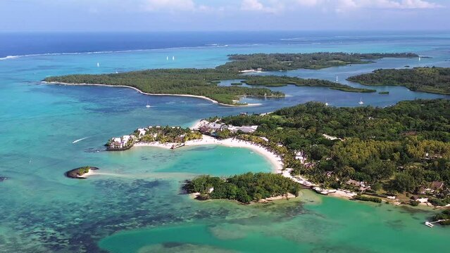 Panoramic aerial view of ShangriLa Le Touessrok and Ilot Mangenie with sailing boats and mountains in the background, Flacq, Mauritius.