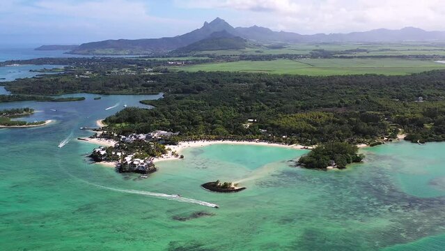 Panoramic aerial view of ShangriLa Le Touessrok and Ilot Mangenie with sailing boats and mountains in the background, Flacq, Mauritius.