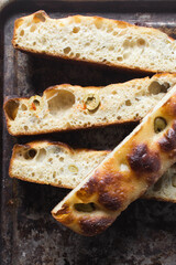 homemade olive focaccia on a baking tray, Flatlay of focaccia with green olive topping, fresh homemade focaccia bread