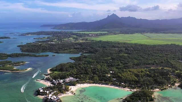 Panoramic aerial view of ShangriLa Le Touessrok and Ilot Mangenie with sailing boats and mountains in the background, Flacq, Mauritius.