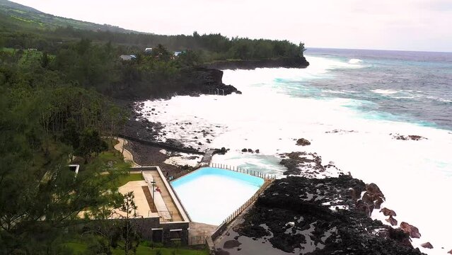 Aerial drone view of Puits des Anglais with an empty pool, natural pool and high breaking waves, Saint-Philippe, Reunion.