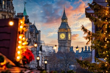 Beautiful sunset view of the Big Ben Clocktower in London, England, with the fairy lights from the Trafalgar Square Christmas market in front