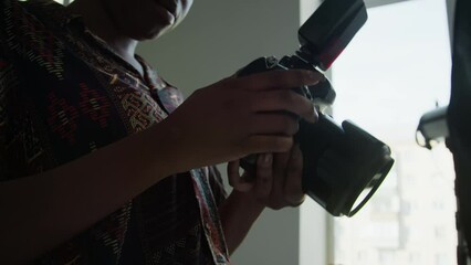 Low angle view of African American female photographer changing camera settings during photoshoot in studio