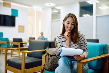 Happy woman going through her data in medical documents at doctor's office.