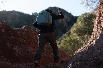 Middle-aged man climbs the mountain in the Garraf Natural Park, supported by hiking poles.