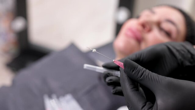 Preparing needles for face thread lifting in a modern clinic. Close-up of a face threadlift needle on an adult client. Facelift concept, surgery, skin rejuvenation.