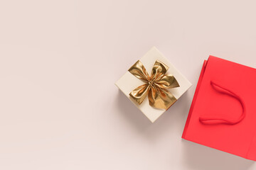 red paper shopping bag and gift box with a gold bow on a pink background, top view