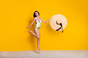 Full length photo of funky cheerful lady wear swimsuit jumping high holding sun headwear empty...
