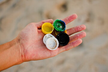 Hand Holding Assorted Multicolored Plastic Bottle Caps at the Beach, Brazil