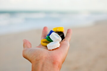 Hand Holding Assorted Multicolored Plastic Bottle Caps at the Beach, Brazil