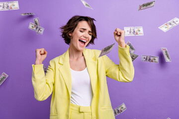 Photo of lucky lottery winner girl raise fists up screaming her huge jackpot falling dollars banknotes isolated on purple color background