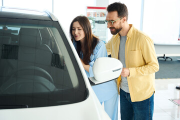 Young couple looking for new auto in car dealership