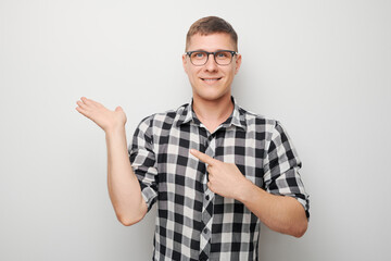 Handsome man in glasses holding something in hand, demonstrating empty space for product or text...