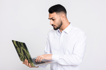 Sussessful delighted turkish young buisnessman guy holding laptop over grey background in studio...