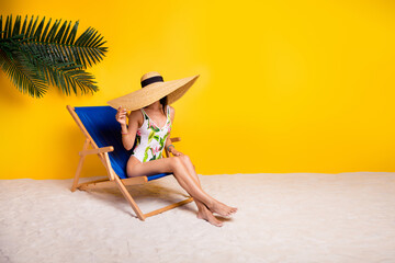 Full length photo of cute shy lady wear swimsuit enjoying sun bathing lounge chair empty space isolated yellow color background