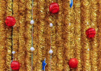 Christmas ornaments on a golden tinsel background. Lights, ball, star are used to festoon the celebration.