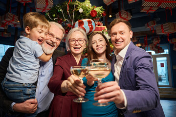 Happy family clinking glasses with champagne at Christmas dinner in restaurant