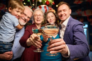 Clinking glasses with champagne in hands of group of people at Christmas