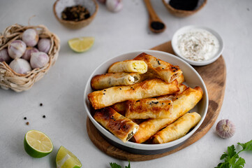 Turkish Cigara Börek (Sigara böreği) or Cigarette Pastry with Spinach and Feta Cheese with yogurt dip. Finger food. Spring rolls. Top view