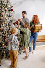 family time on eve Christmas, decorate together fir tree by colorful balls and garlands. feel happy...