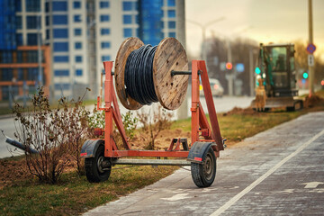 Wooden reel with fiber optic cable mounted on trailer for easy transportation. Laying optical fiber...