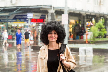 A woman in a short black dress walks quickly in the rain to avoid getting wet.