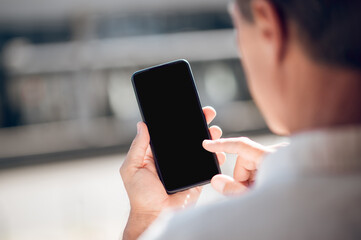 Back view of man looking to mobile phone with empty display with advertisement area.