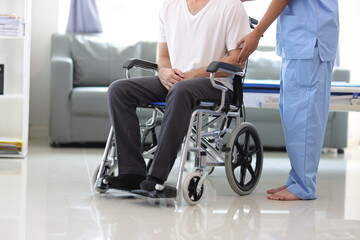 Fototapeta na wymiar Doctor is inquiring about the condition of a patient with a leg injury in a hospital examination room. Nurse caring for the condition of a man in a wheelchair in a hospital.