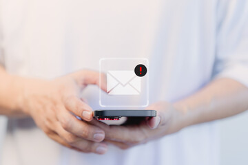 User hand using a mobile phone with an email icon, Email alert with a caution warning sign for notification error. Security protection on the internet, junk mail, and compromised information. - obrazy, fototapety, plakaty