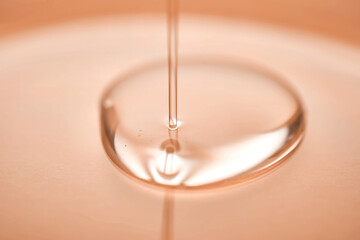 A juicy drop of gel on a Peach Fuzz background. - obrazy, fototapety, plakaty