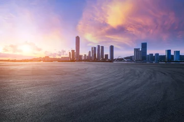 Schilderijen op glas Asphalt road square and city skyline with modern buildings at sunset  © ABCDstock