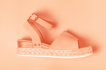 Female sandal close-up against the background color of the year 2024 Peach Fuzz.