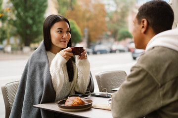Smiling couple drinking coffee while sitting in cafe outdoors