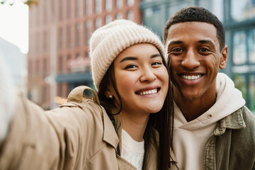 Beautiful couple taking selfies and smiling while standing at street