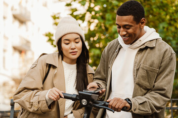 Couple paying online with smartphone while renting electric scooter in park