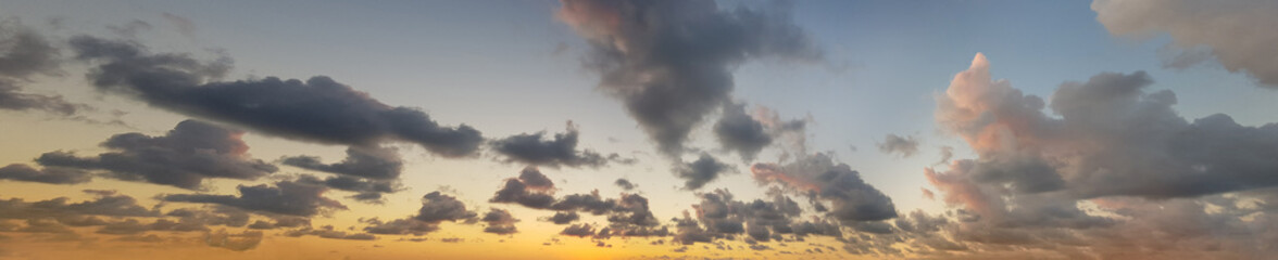 Fototapeta na wymiar Sky panorama. Sunset sky with golden sun and colorful bright summer cloud