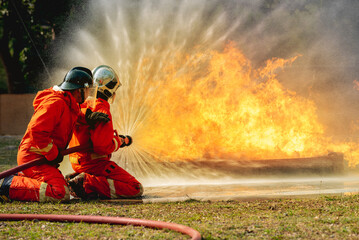 firefighter training fireman team use extinguish spraying fire oil station training. Fire fighter...