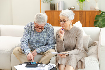 Middle aged senior couple sit with laptop and paper document. Older mature man woman reading paper...