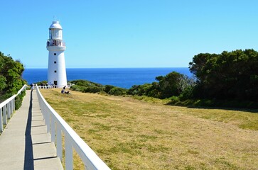 Fototapeta na wymiar A white lighthouse on the rocky coast of the Pacific Ocean at the Cape of Good Hope South Australia near Melbourne,