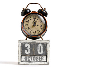 October 30 on wooden calendar with alarm clock white background.