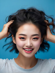 Beautiful young Asian woman with clean fresh skin and touching Hair, Enjoying the freedom a blue background 