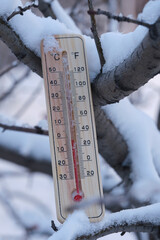Outdoor thermometer standing in snow in cold frosty weather.