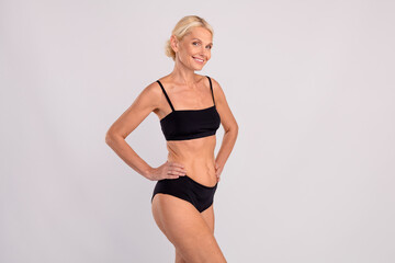 Fototapeta premium Photo of charming thin pensioner elderly woman posing showing her slim body underwear shopping advert isolated on gray color background