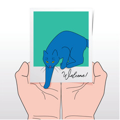 Cat Stepping On Outstretched Hands From Instant Print Photograph With Written Word “Welcome!” Referring To Rescuing, Fostering, Adopting A New Pet Cat Into A New Family From The Shelter, Homelessness