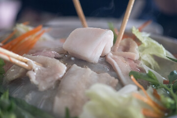 Pork on a hot plate, an aluminum dome grill is placed on a clay fire pot fueled by charcoal at the...