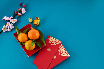 Chinese New Year. Red packet envelope, flowers, mandarins, festival decorations on teal color...