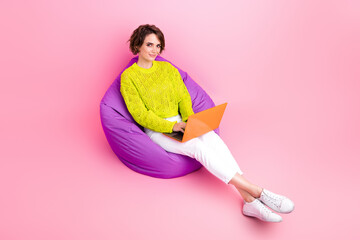 Full length photo tow view of charming pretty girl dressed neon sweater sitting bean bag texting...