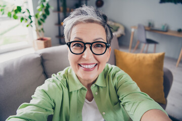 Self portrait of positive toothy smiling mature age businesswoman wear khaki green shirt recording...